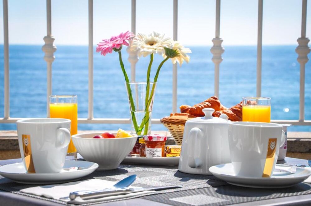 Petit-déjeuner en terrasse vue mer, croissants et fleurs.