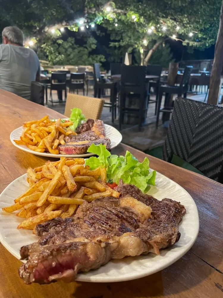 Steak frites avec salade sur table en terrasse.