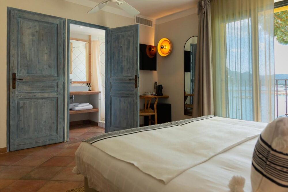 Chambre lumineuse avec vue extérieure et salle de bain.