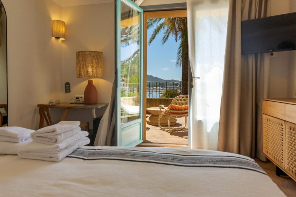 Chambre lumineuse avec vue sur terrasse et mer.