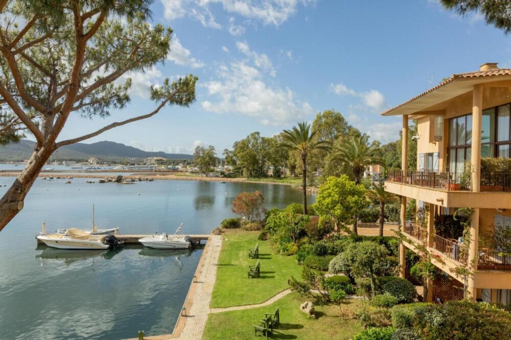 Maison en bord de mer avec jardins et bateaux.