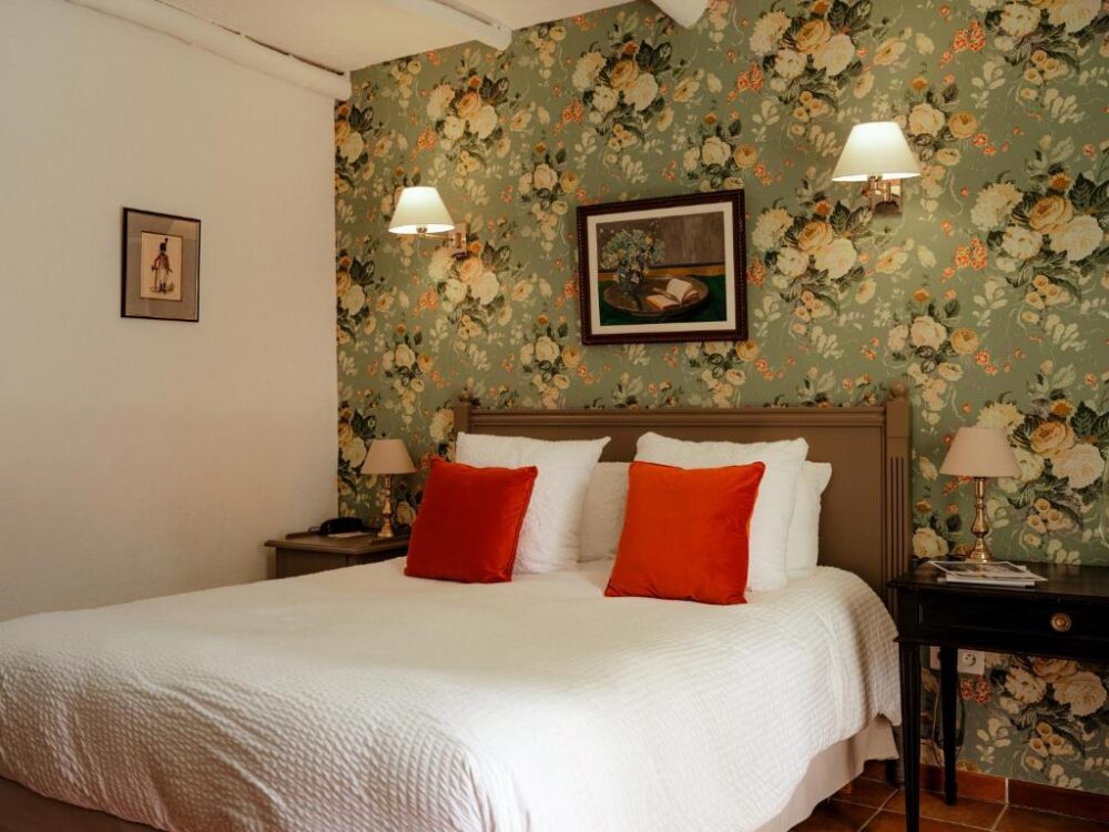 Chambre avec lit double et papier peint fleuri.