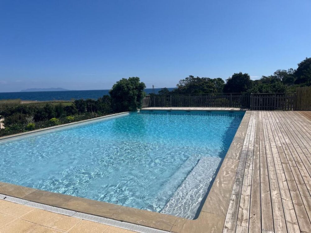 Piscine avec vue sur la mer et jardin.
