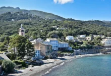 Côte méditerranéenne avec village et collines verdoyantes.
