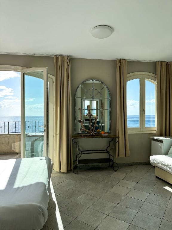 Chambre lumineuse avec vue sur mer depuis balcon.