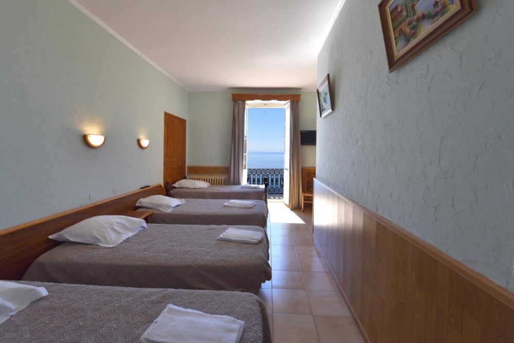 Chambre avec trois lits et vue sur la mer.