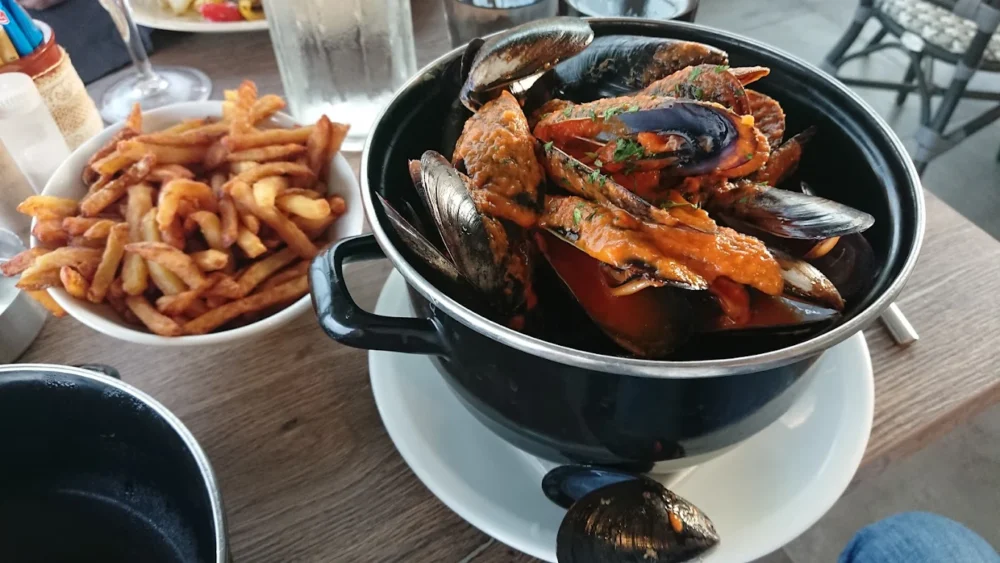 Moules-frites servies avec sauce tomate épicée.