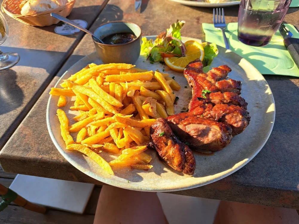Assiette de viande grillée avec frites, salade, sauce.