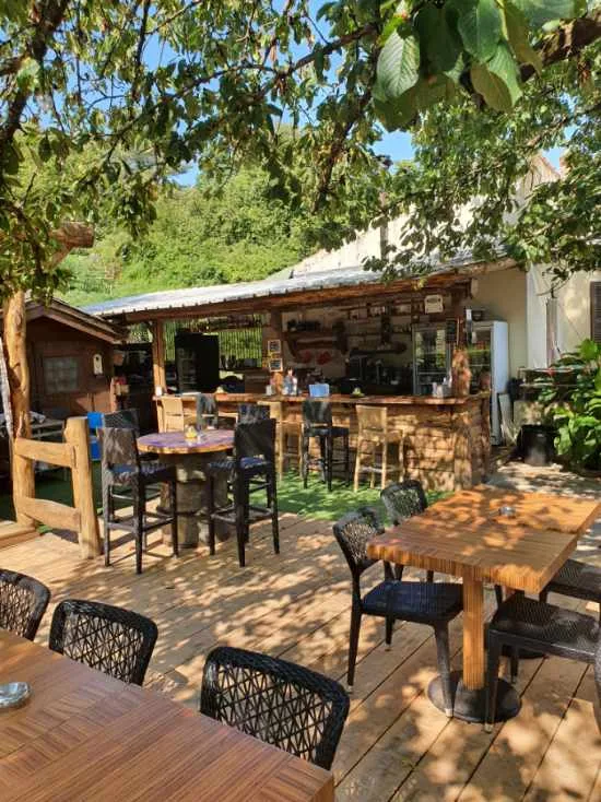 Terrasse extérieure avec tables en bois sous les arbres.