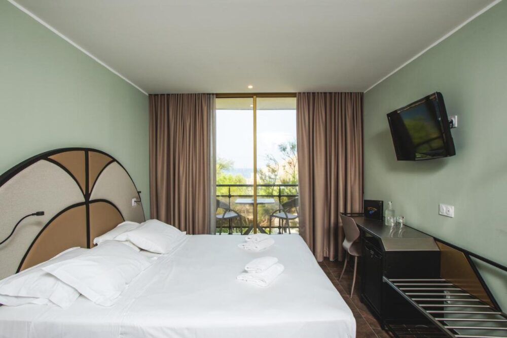 Chambre d'hôtel avec balcon et vue sur jardin.