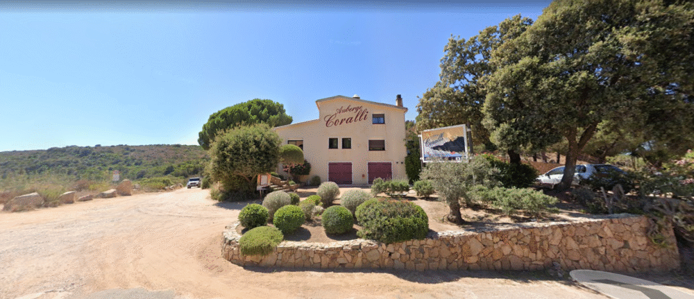 Auberge avec jardin et parking sous ciel bleu.