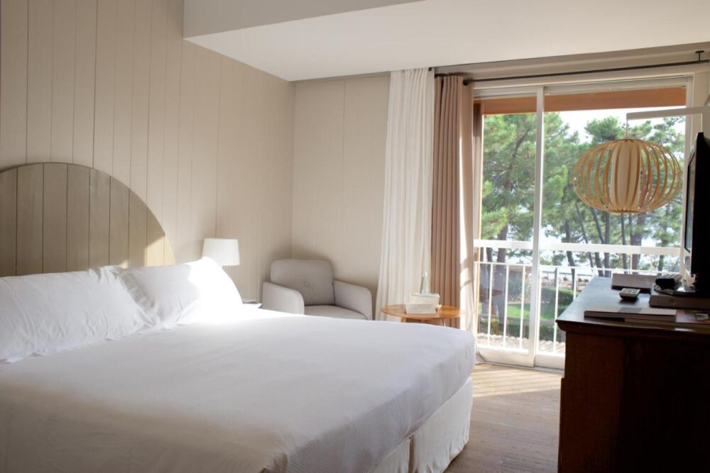 Chambre d'hôtel lumineuse avec vue sur balcon.