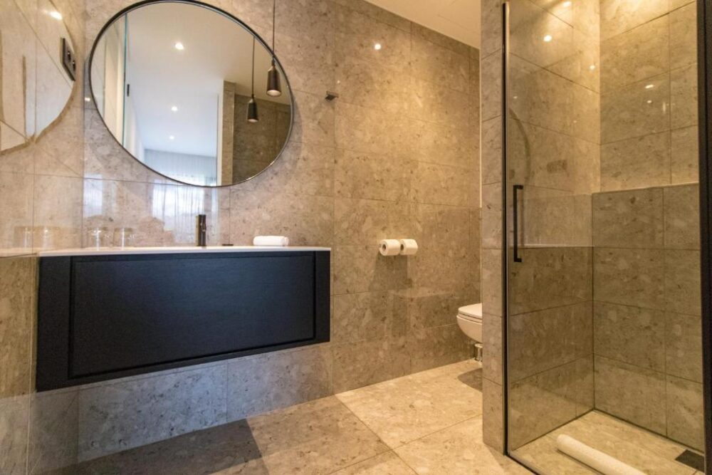 Salle de bain moderne avec douche et miroir circulaire.