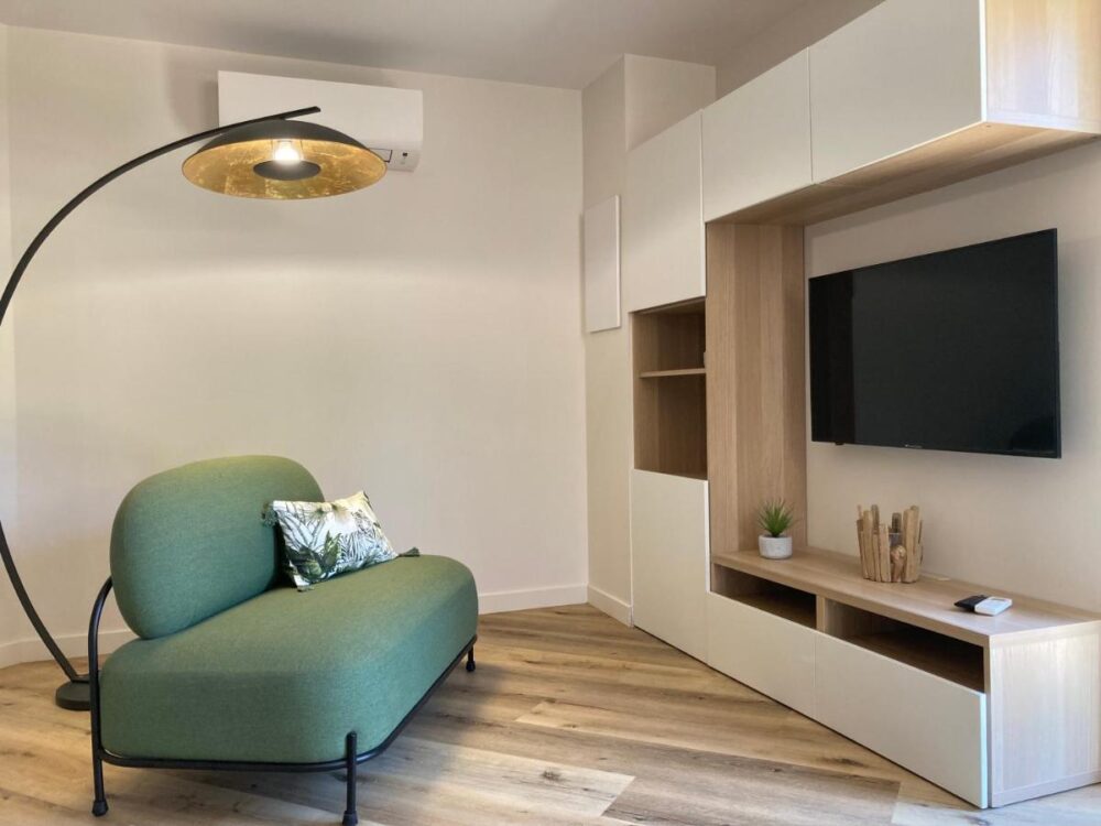 Salon moderne avec canapé vert et télévision.