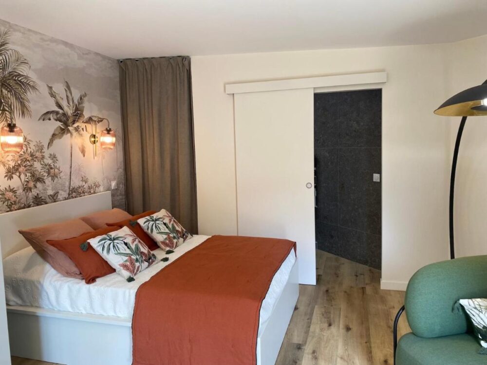 Chambre moderne avec lit et décorations tropicales.