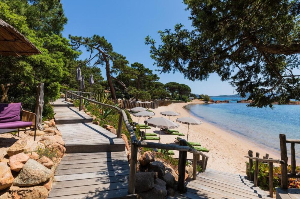 Plage avec parasols, mer et pont en bois.
