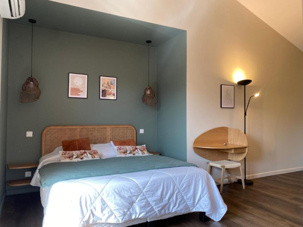 Chambre moderne avec lit double, bureau et lampadaire.
