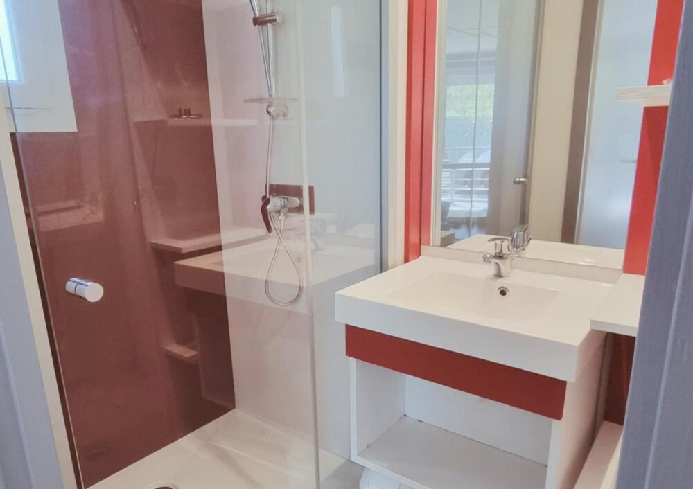 Salle de bain moderne avec douche et lavabo.