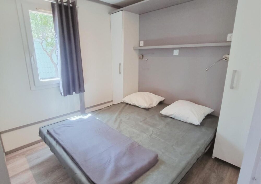 Chambre minimaliste avec lit double et fenêtre.