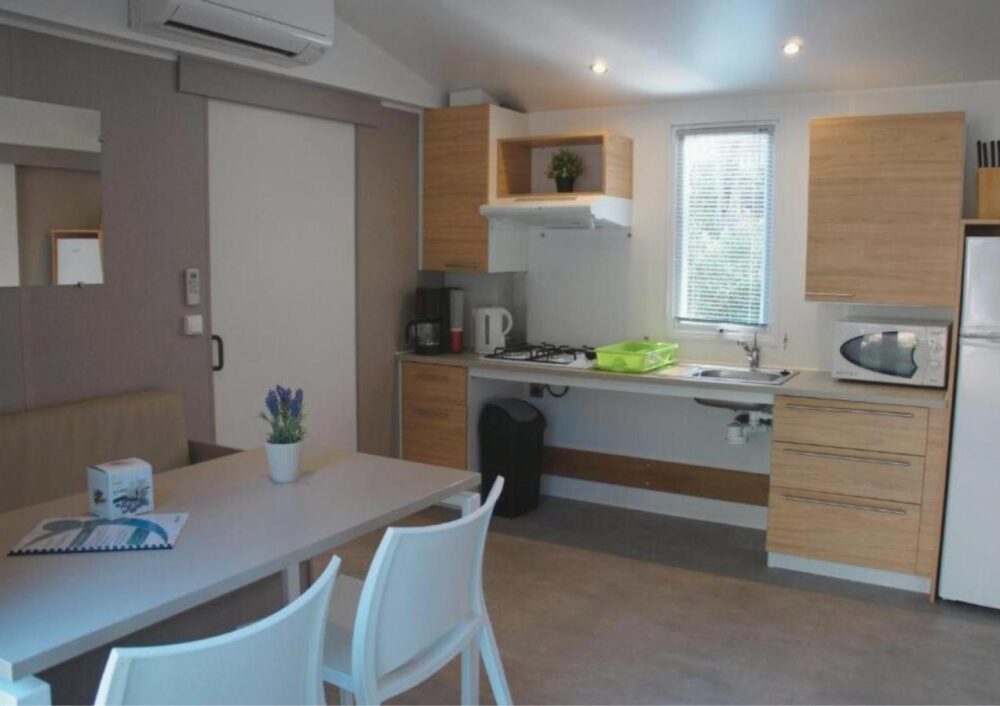 Cuisine moderne avec table, chaises et électroménager.