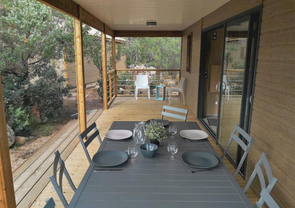 Terrasse en bois avec table et chaises grises.