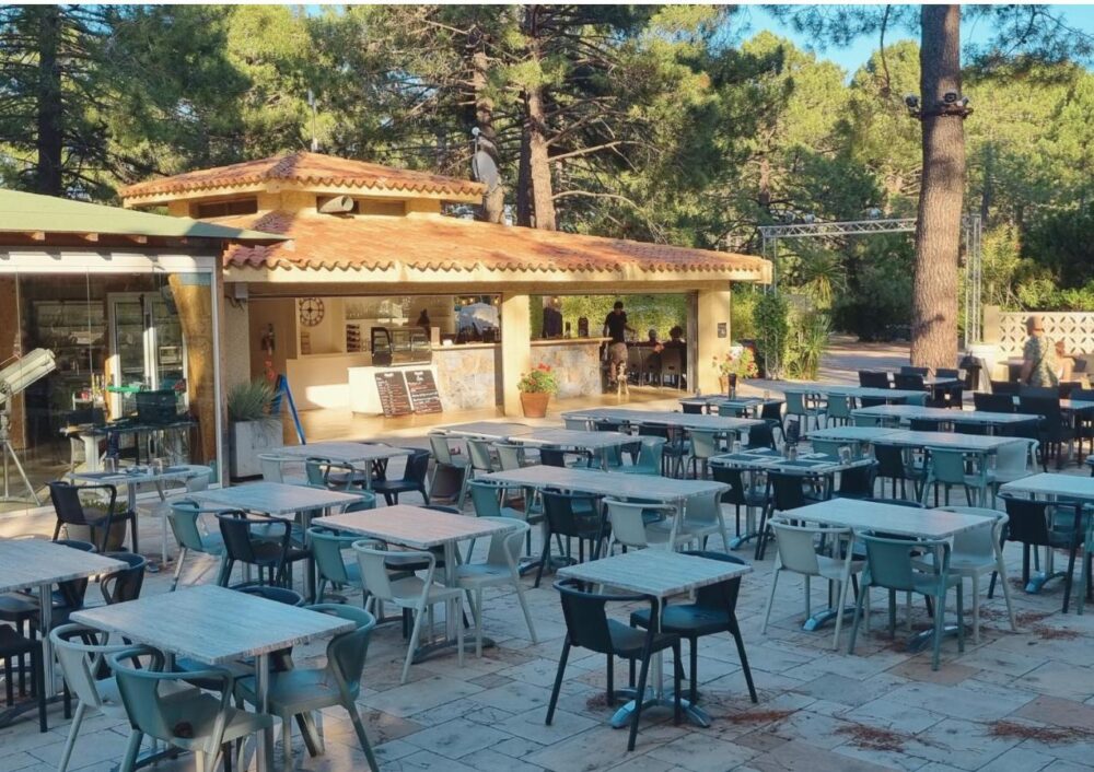 Terrasse vide avec tables et chaises grises.