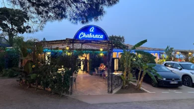 Restaurant avec enseigne bleue et terrasse éclairée.