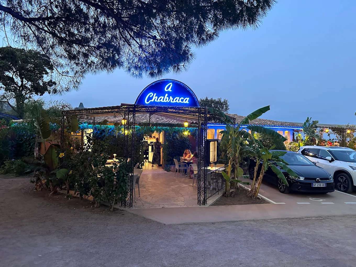 Restaurant avec enseigne bleue et terrasse éclairée.
