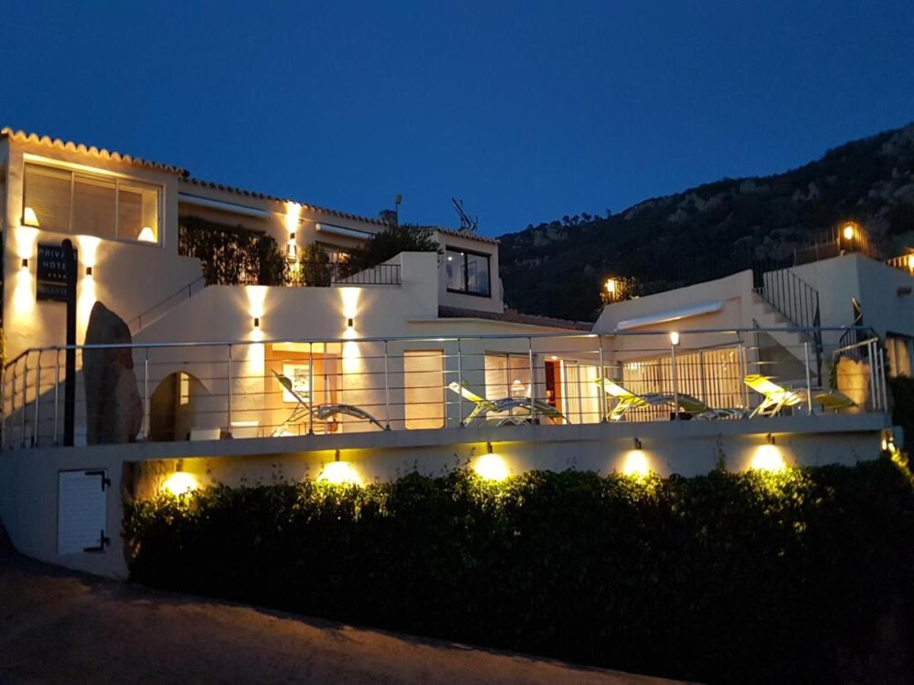 Hôtel illuminé la nuit avec terrasse.