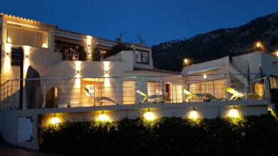 Hôtel illuminé la nuit avec terrasse.