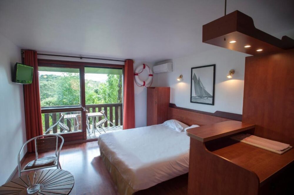 Chambre d'hôtel avec balcon et vue sur nature.