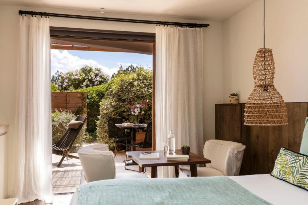 Chambre lumineuse avec terrasse et jardin verdoyant.