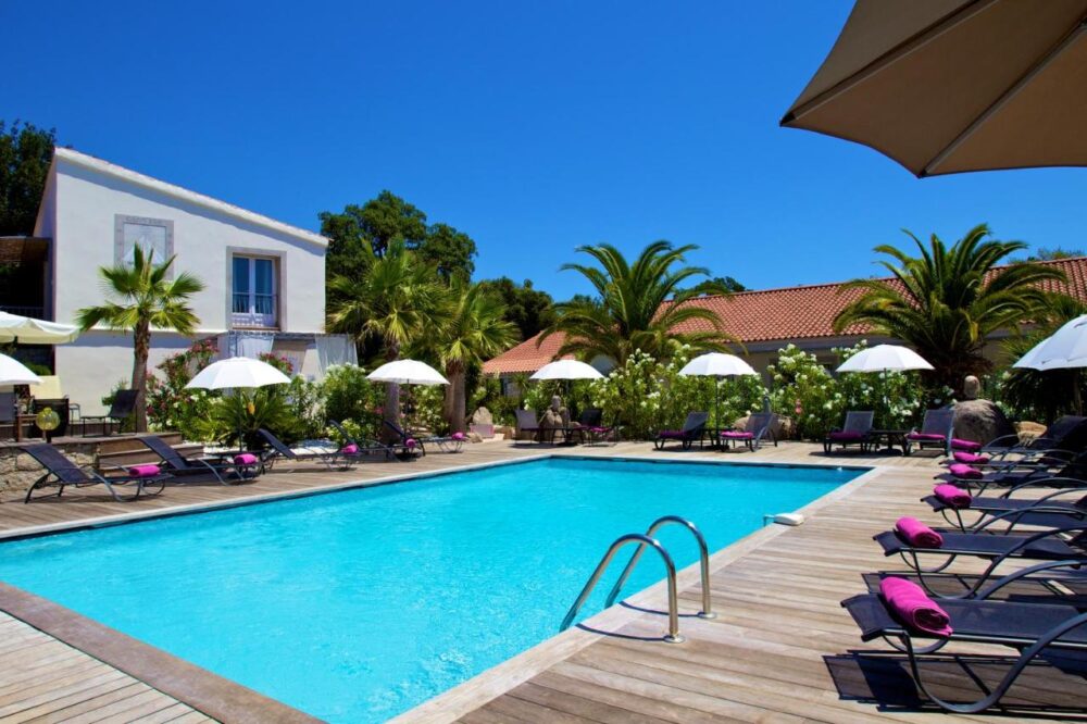 Piscine extérieure avec chaises longues et parasols.