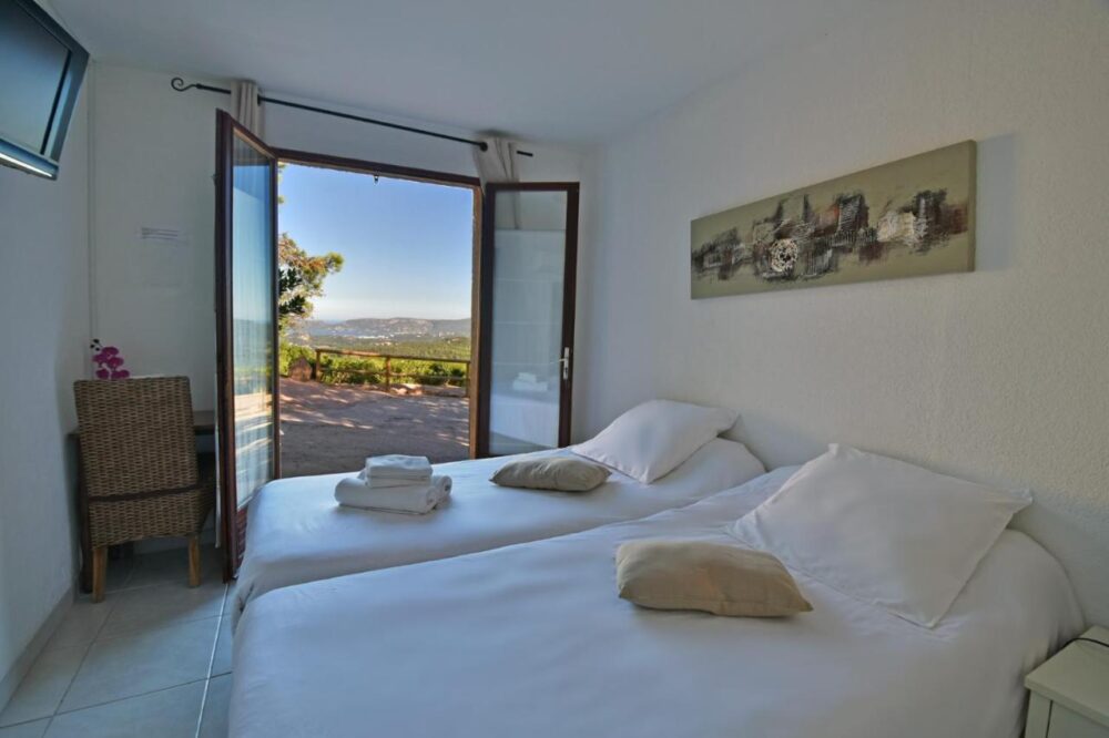 Chambre avec vue sur jardin et montagnes lointaines.