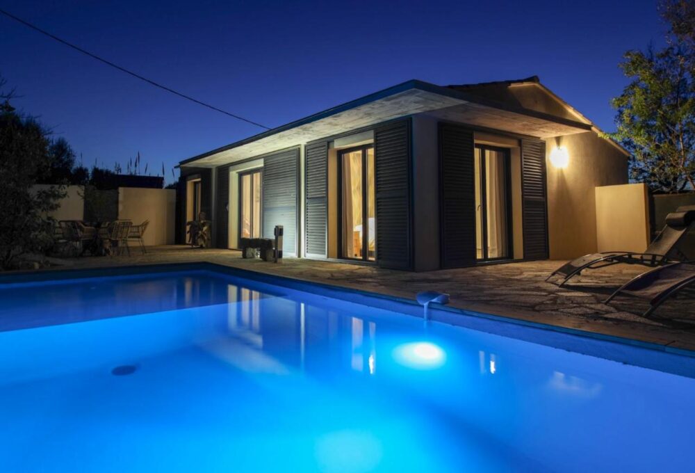 Maison moderne avec piscine éclairée la nuit.