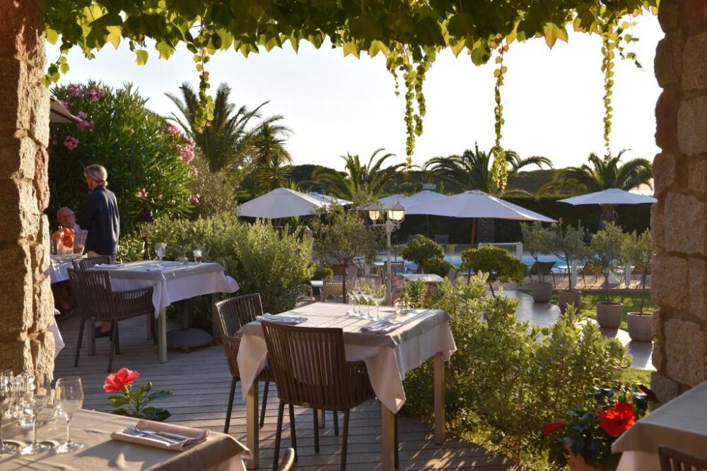 Terrasse de restaurant avec vue sur jardin et piscine.