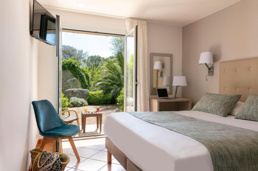 Chambre lumineuse avec terrasse et jardin verdoyant.