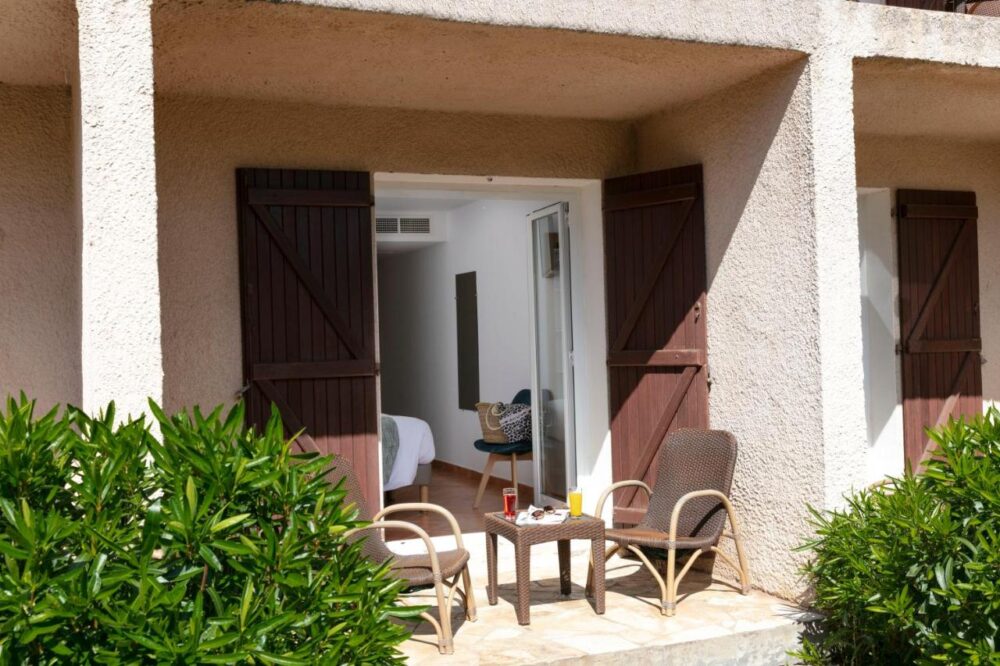 Terrasse d'une chambre avec chaises et boissons.