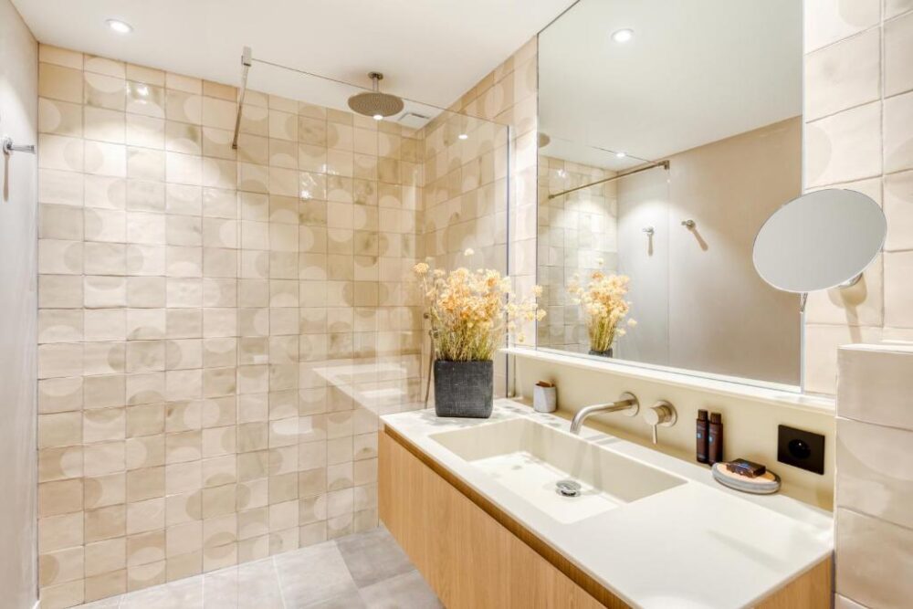 Salle de bain moderne avec douche et vasque blanche.