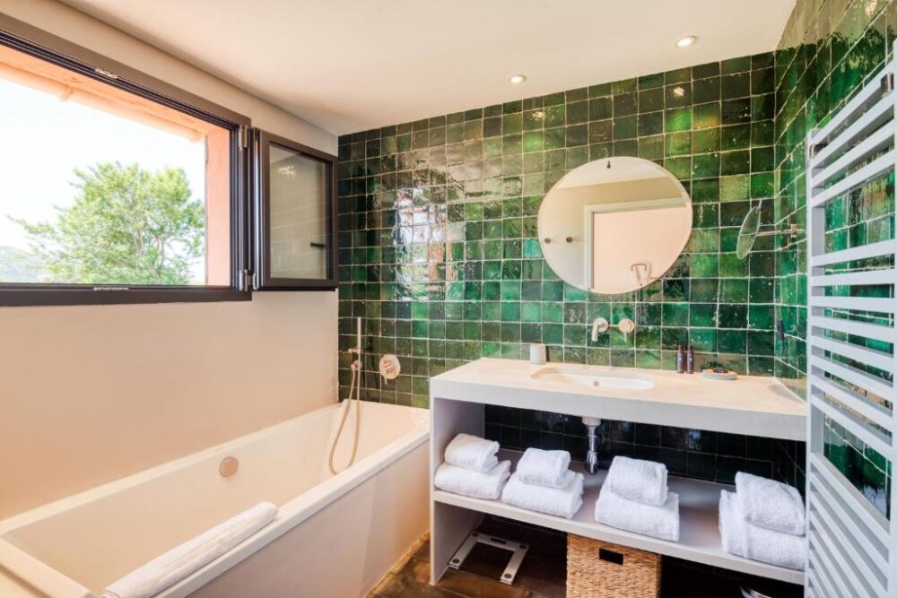 Salle de bain avec carrelage vert et baignoire
