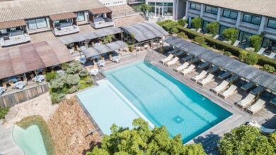 Hôtel avec piscine extérieure et chaises longues.