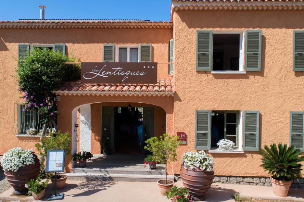 Façade d'un hôtel avec enseigne et plantes.