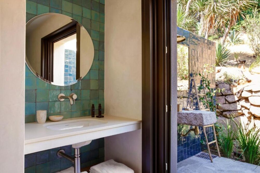 Salle de bain extérieure avec lavabo et miroir.