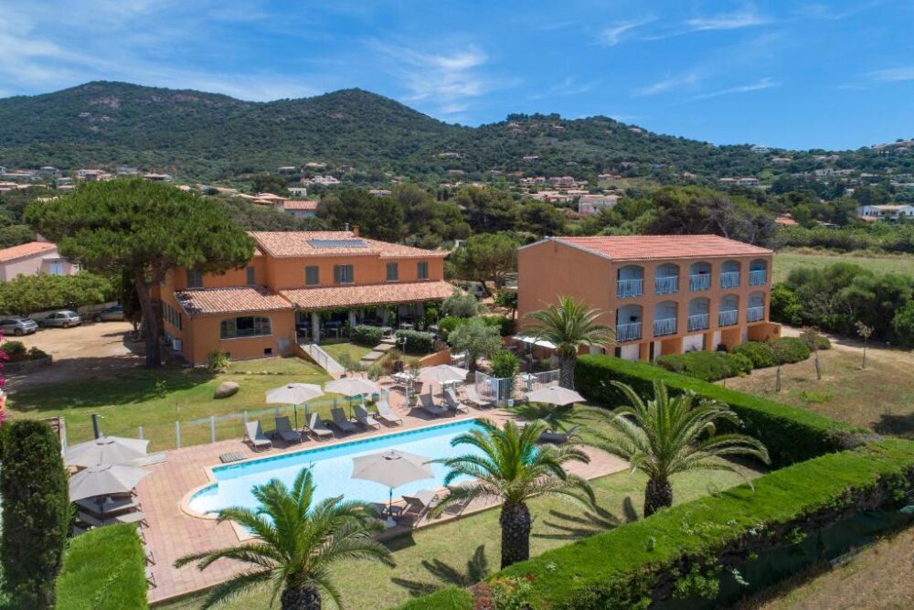 Hôtel avec piscine et montagnes en arrière-plan.