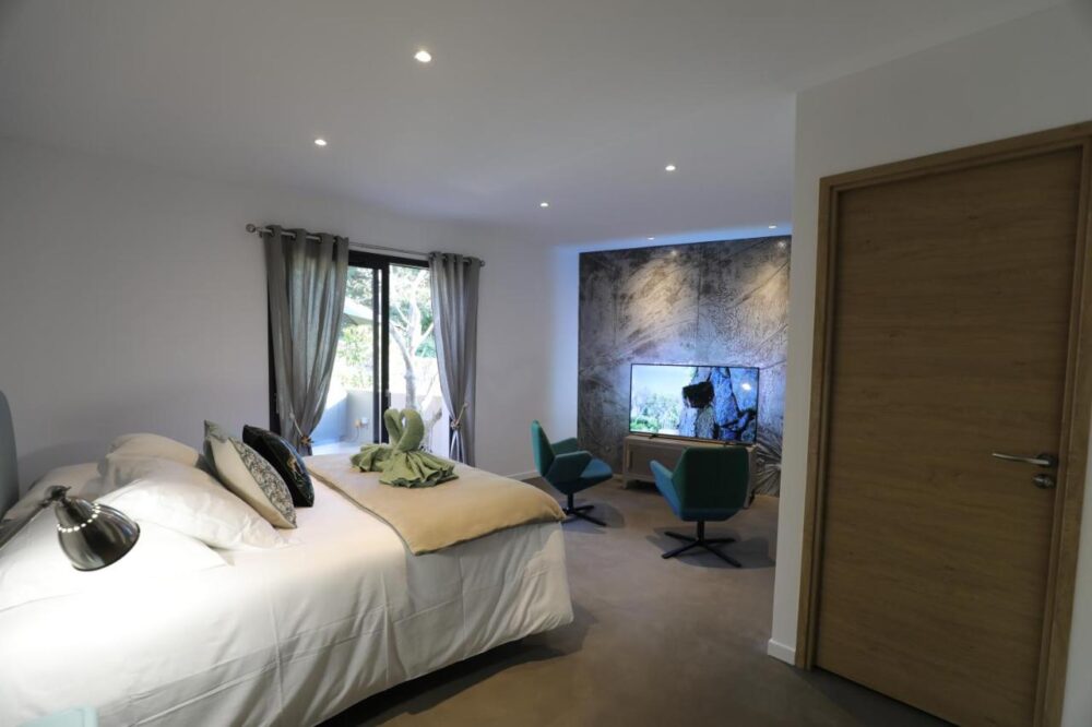Chambre moderne avec lit et fauteuils verts.