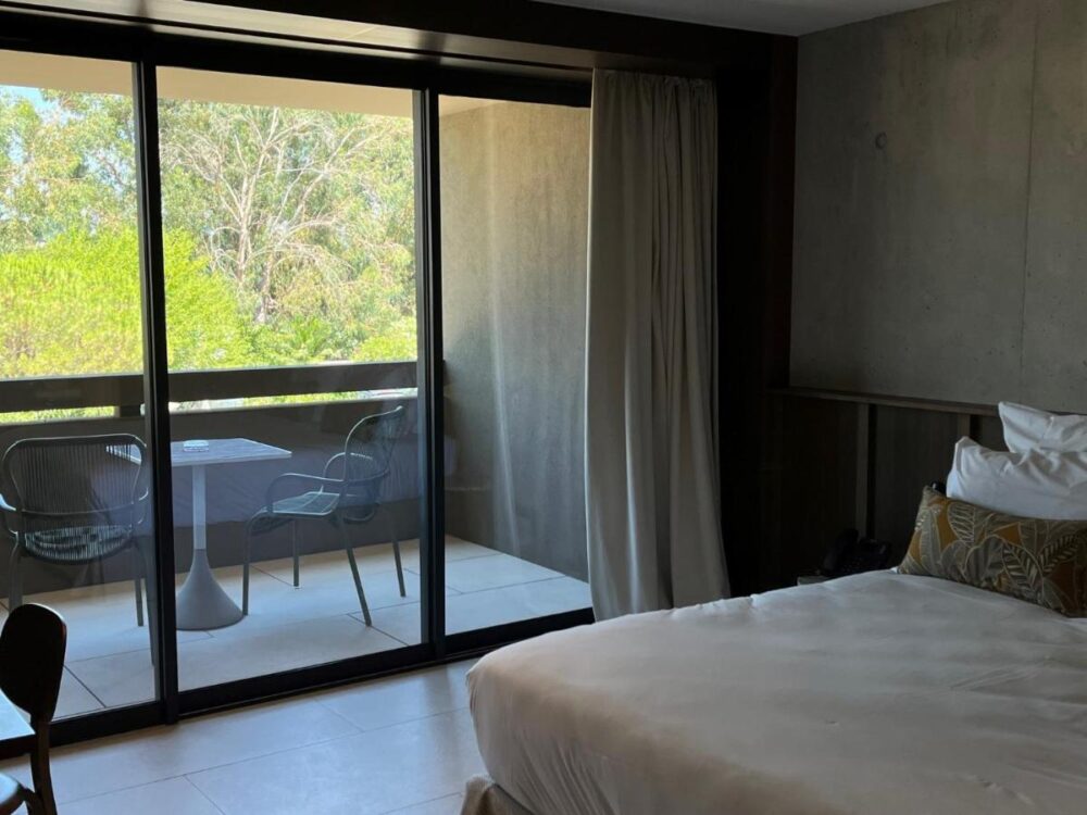 Chambre d'hôtel avec balcon et vue sur jardin.