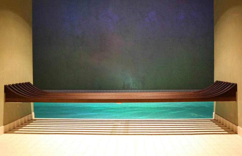 Banc en bois moderne au-dessus d'une piscine intérieure.