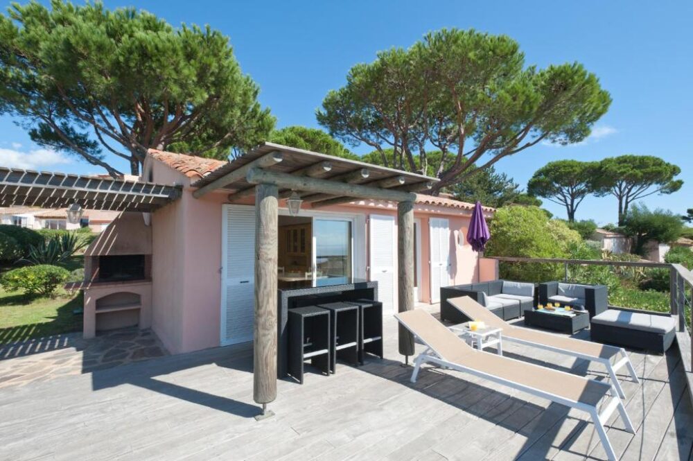 Terrasse ensoleillée avec chaises longues et canapé.