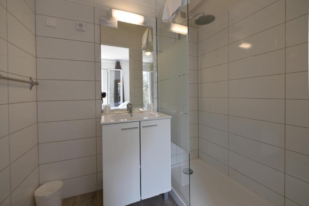Salle de bain moderne avec douche et lavabo.