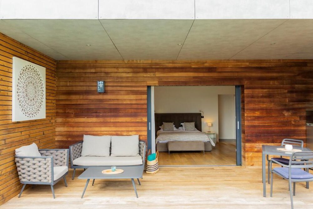 Terrasse en bois avec mobilier moderne et chambre ouverte.
